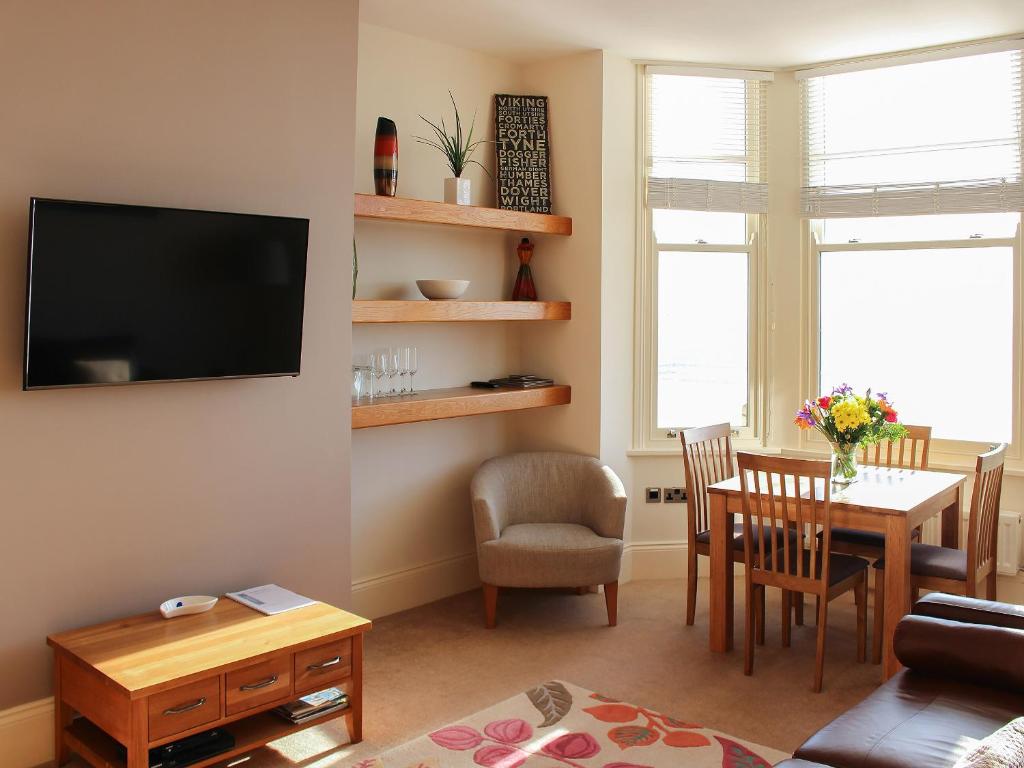 a living room with a television and a table and chairs at Apartment 2 in Filey