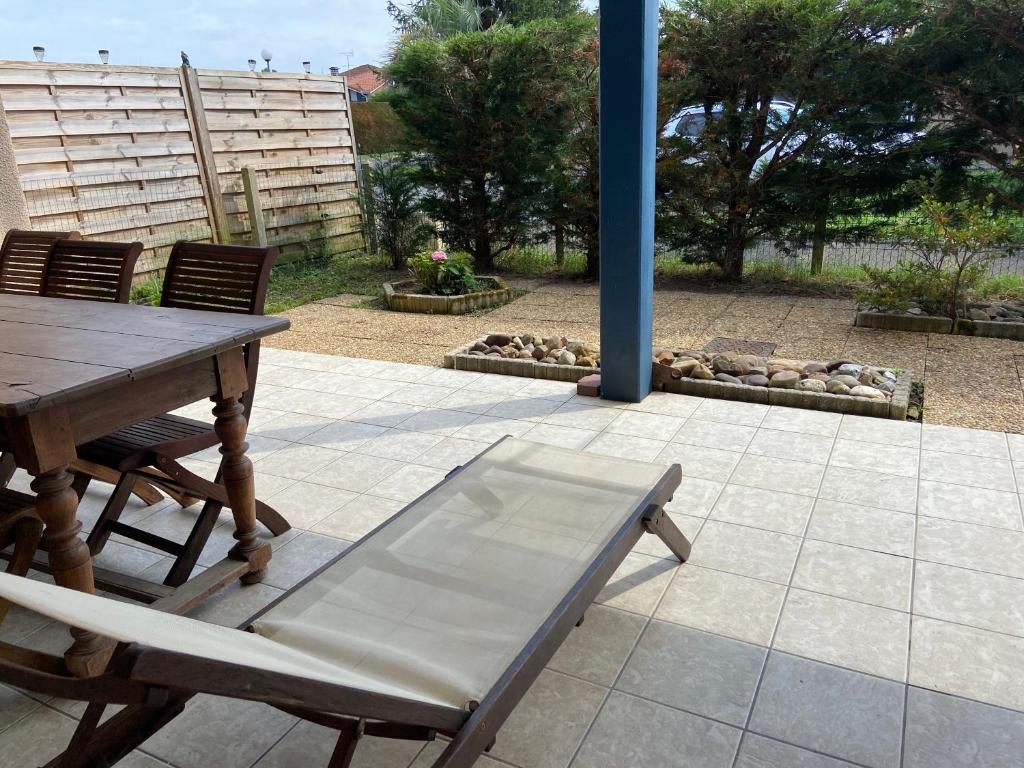 une terrasse avec une table, des chaises et une cheminée dans l'établissement Grand appartement en résidence calme avec piscine, à Saint-Paul-lès-Dax