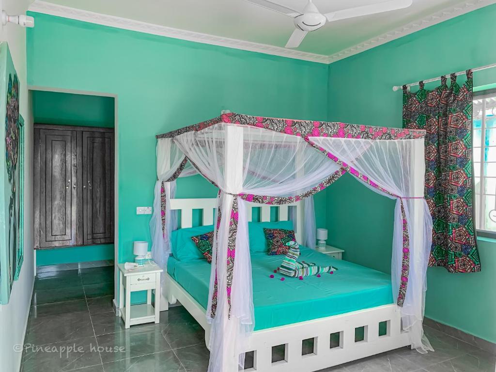 a bedroom with blue walls and a bed with a canopy at Pineapple House in Nungwi