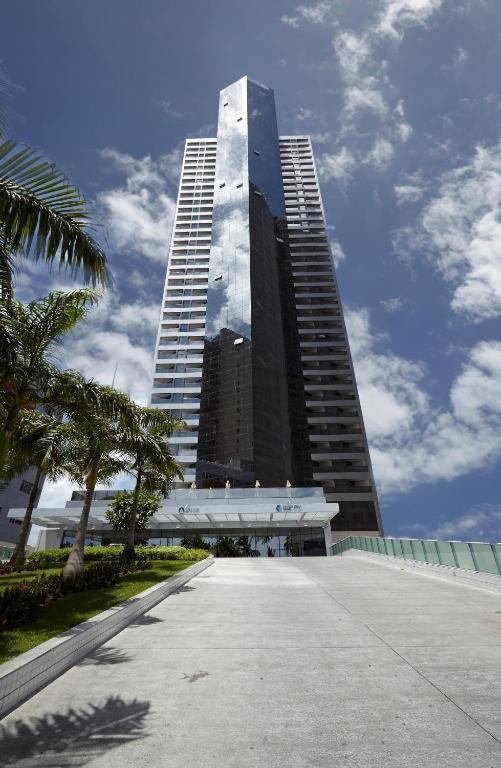 a tall building in front of a large building at Flat Beira Mar Boa Viagem- Beach Class Internacional-Família in Recife