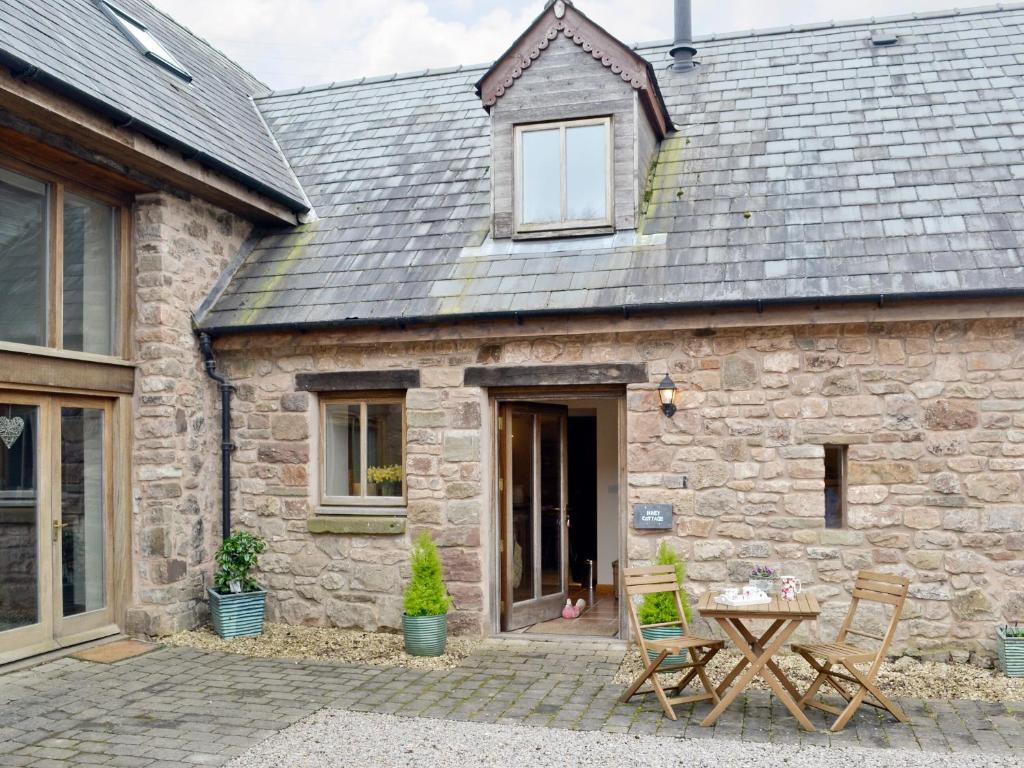 ein Steinhaus mit einem Tisch und Stühlen davor in der Unterkunft Honey Cottage in Newland