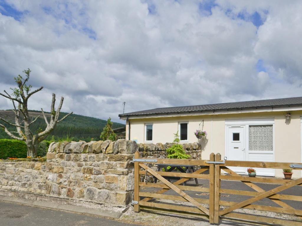 a house with a gate and a stone wall at Stable Cottage - Ukc645 in Byrness