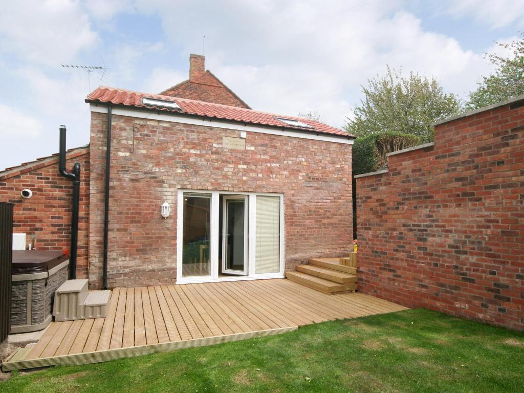 a brick house with a deck in the yard at Barn Cottage - E5560 in Winthorpe