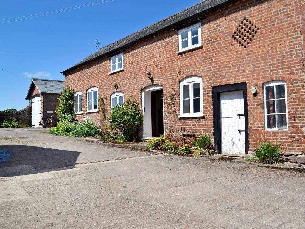 a brick building with a white door and a driveway at The Grooms Cottage in Ashperton