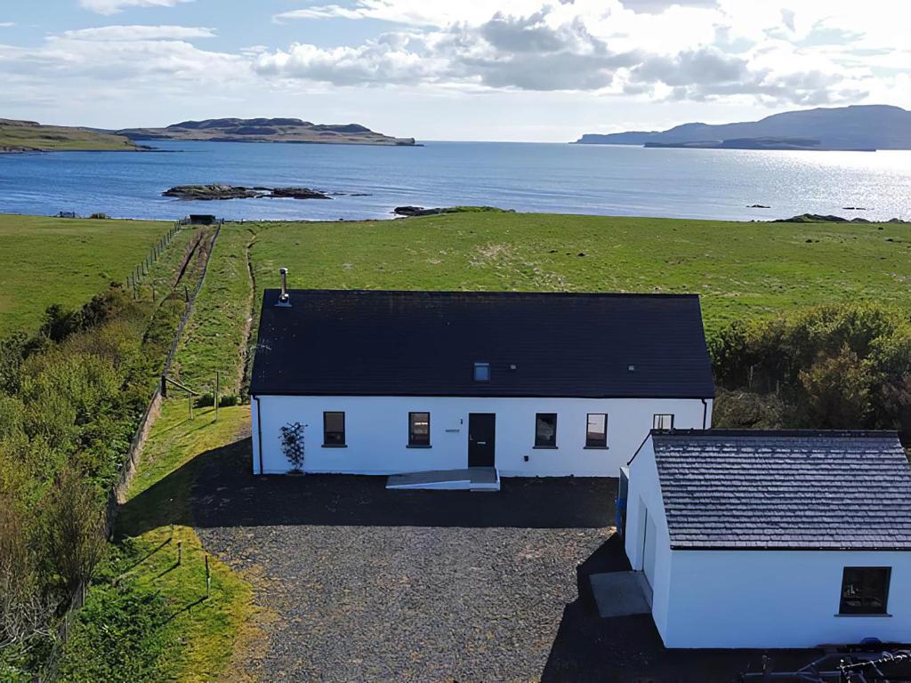 a white house with a black roof next to a body of water at Hygge in Eabost