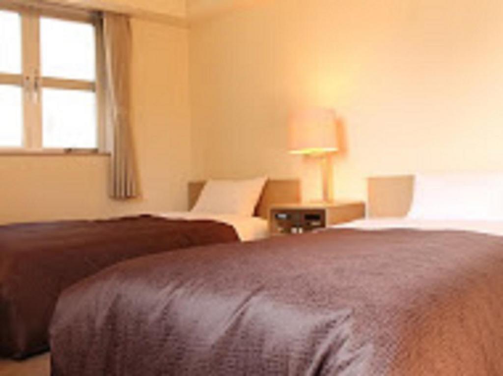 Postel nebo postele na pokoji v ubytování HOTEL LiVEMAX BUDGET Fuchu Annex