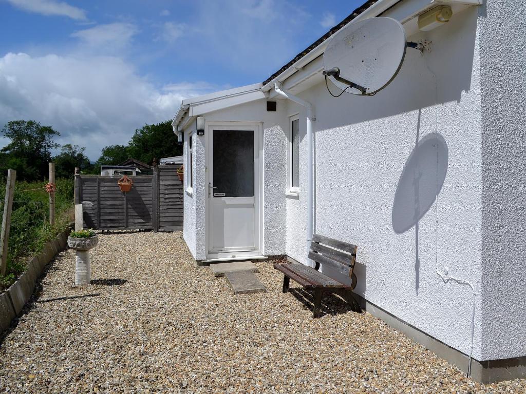 a white building with a door and a bench at Russets East Wing in Isle Brewers