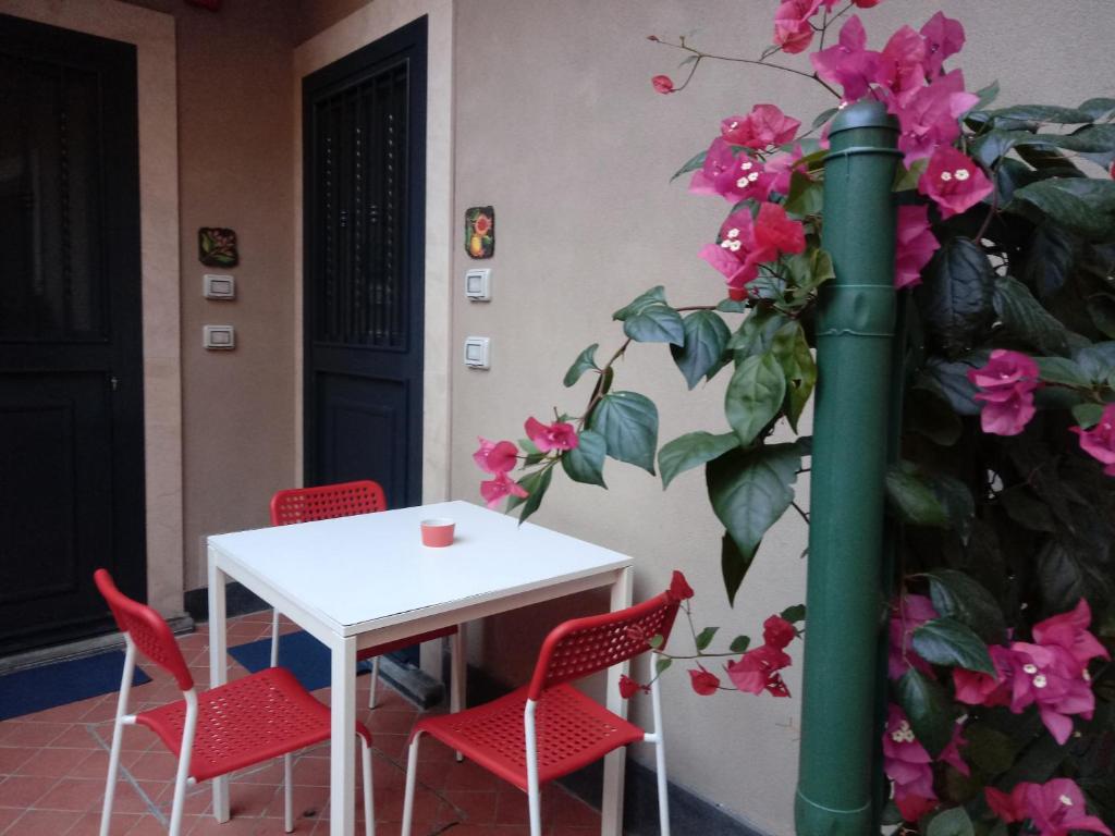 uma mesa e cadeiras e uma planta com flores cor-de-rosa em Apartment Melograno5 em Catânia