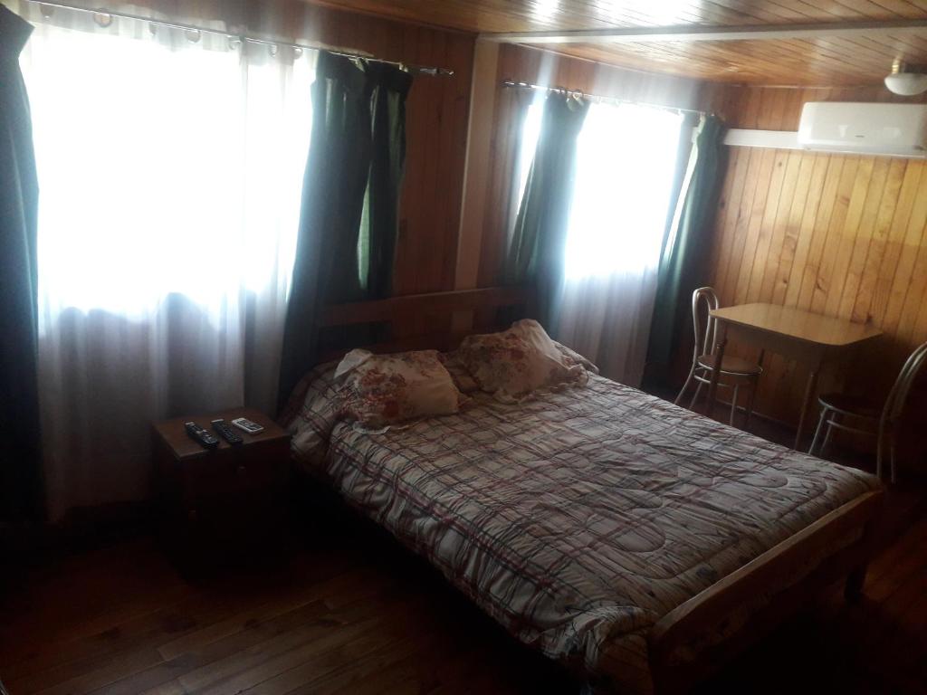 a bedroom with a bed with curtains and a table at Hostal Rayen in Villarrica