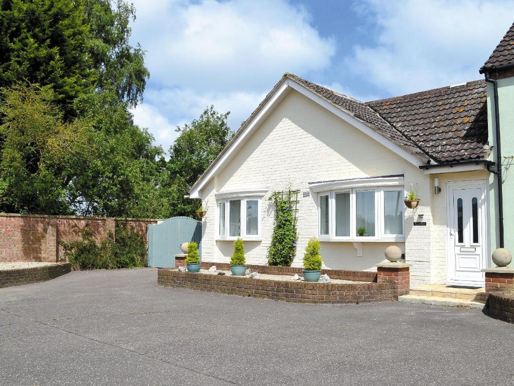 a white house with two potted plants in a driveway at Moors Rest in Sculthorpe