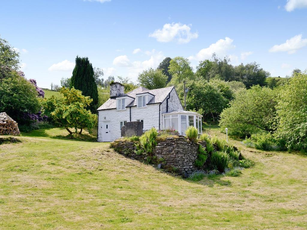 an old white house in a grassy field at Cae Cynddelw in Pale