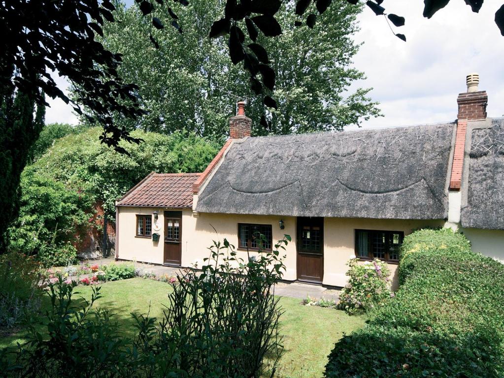 a cottage with a thatched roof in a garden at Rose Cottage - E2352 in Catfield