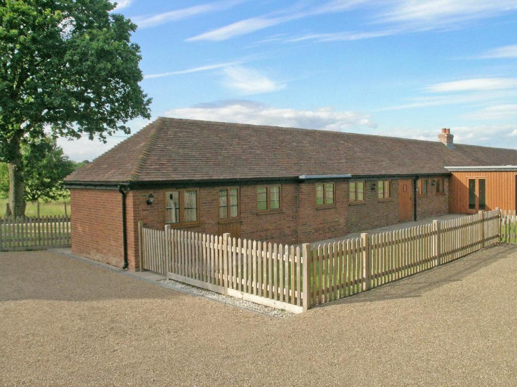 a red brick house with a white fence at Old Dairy Barn in Playden