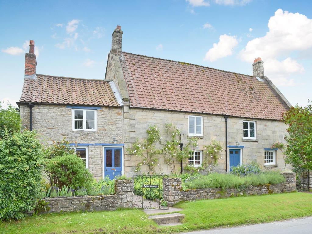 uma antiga casa de pedra com um telhado vermelho em Mill House em Rievaulx