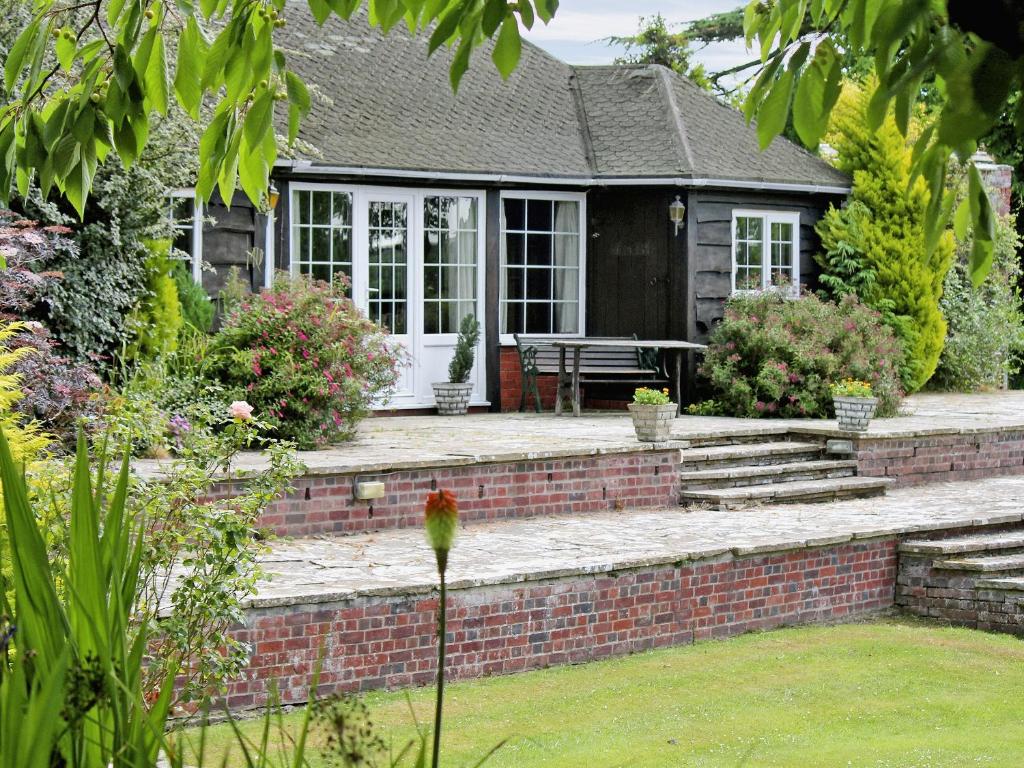 a house with a brick retaining wall and a patio at Summer House in St Asaph