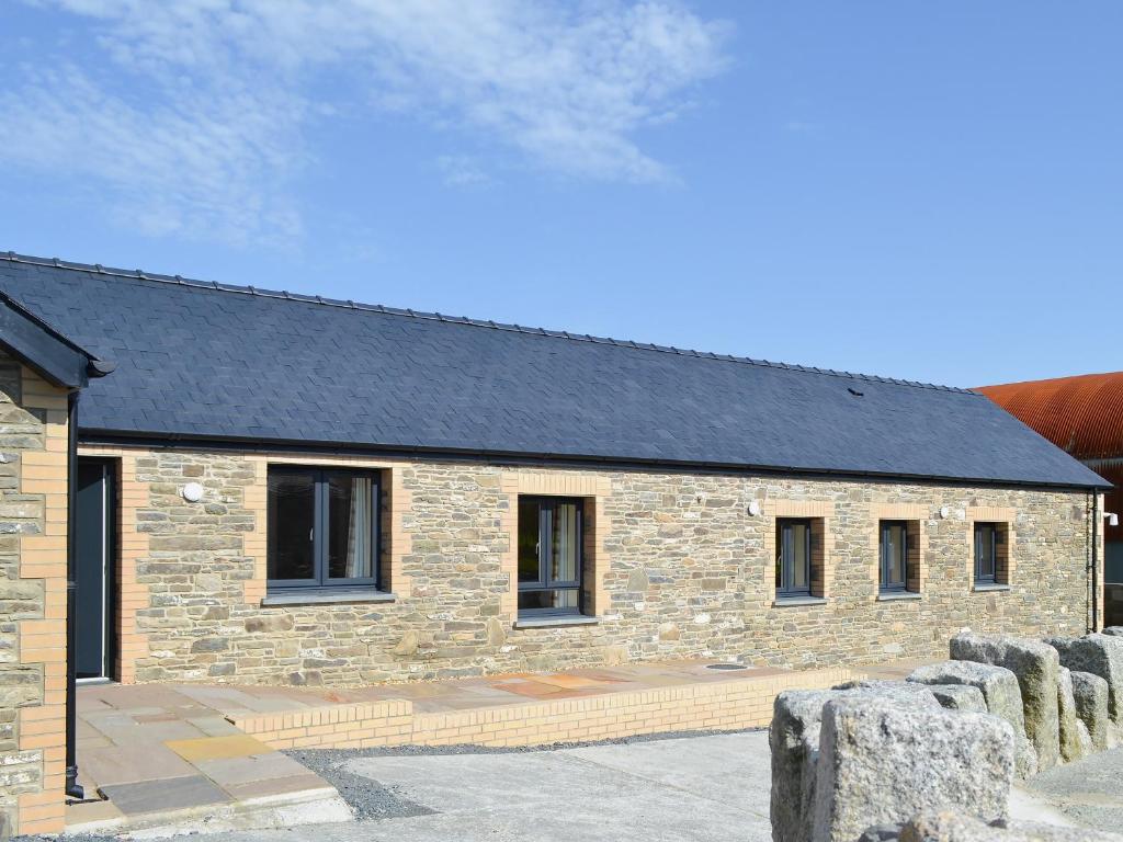 a stone building with a black roof at Roath in Cilcennin