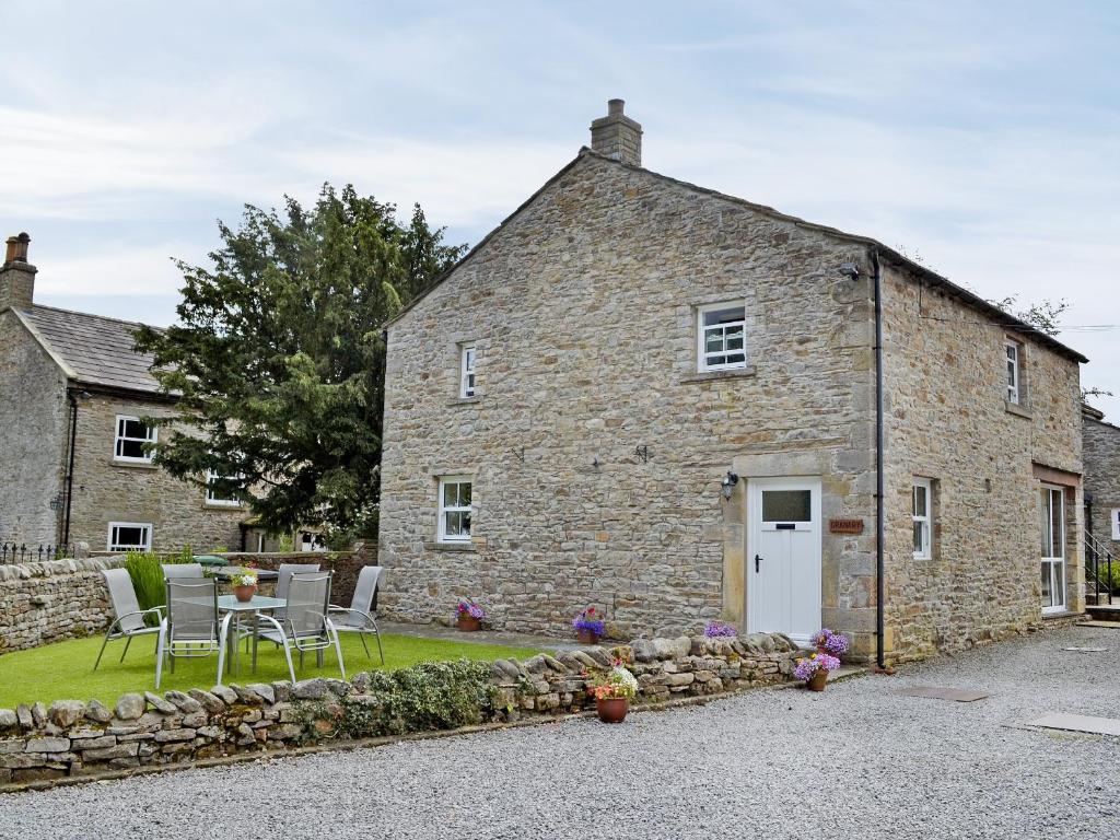 a stone house with a table and chairs in front of it at The Granary in Carperby