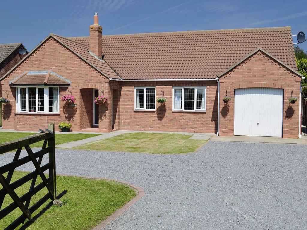 uma casa de tijolos com uma garagem branca em Clydesdale em North Somercotes