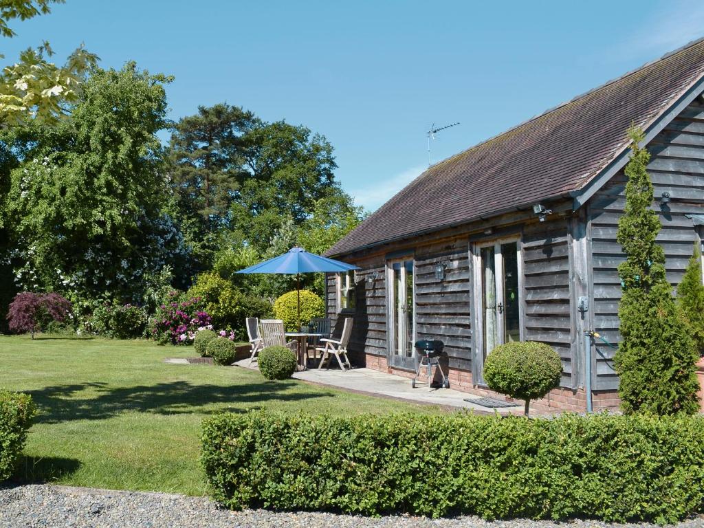 a cottage with a table and an umbrella in the yard at Little Gable in Berrington