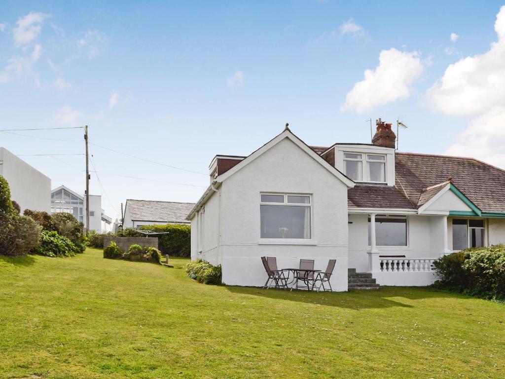 a white house with a table and chairs in the yard at Polmeor in Polzeath