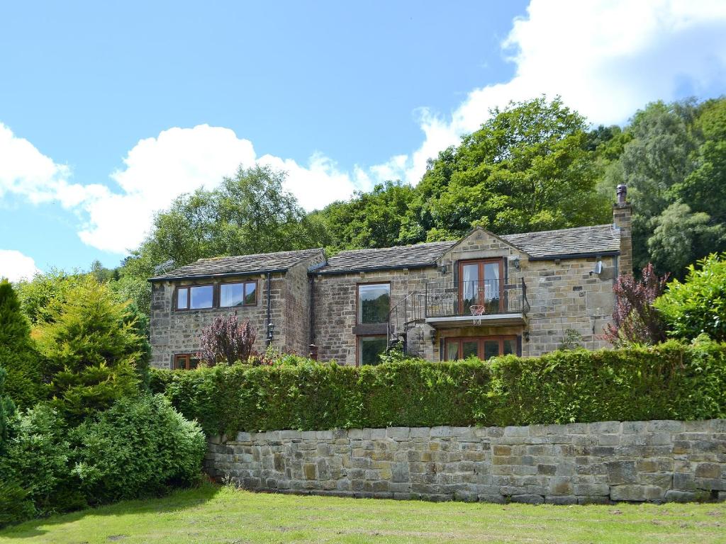 ein altes Steinhaus mit einer Steinmauer in der Unterkunft Lee Cottage in Heptonstall