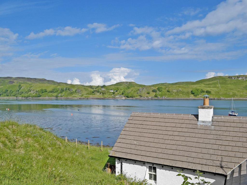 a house next to a body of water with mountains at Ardbhan Croft in Oban