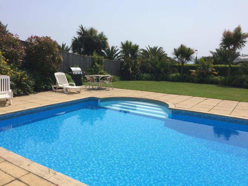 a blue swimming pool with a table and chairs at The Cottage - Goodrington Lodge in Paignton