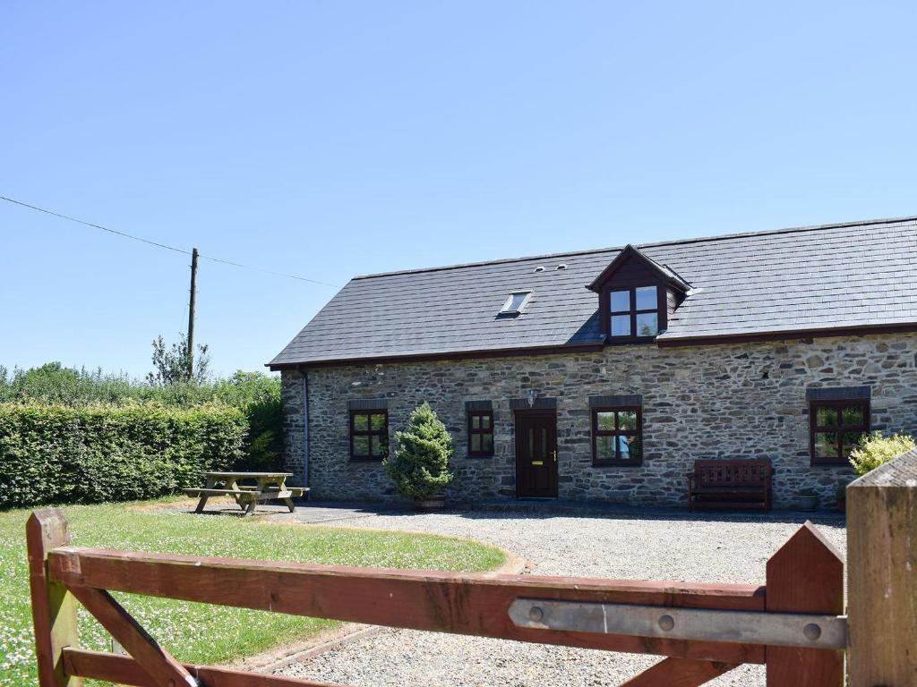 um chalé de pedra com um banco em frente em Ger Yllan em Cross Inn