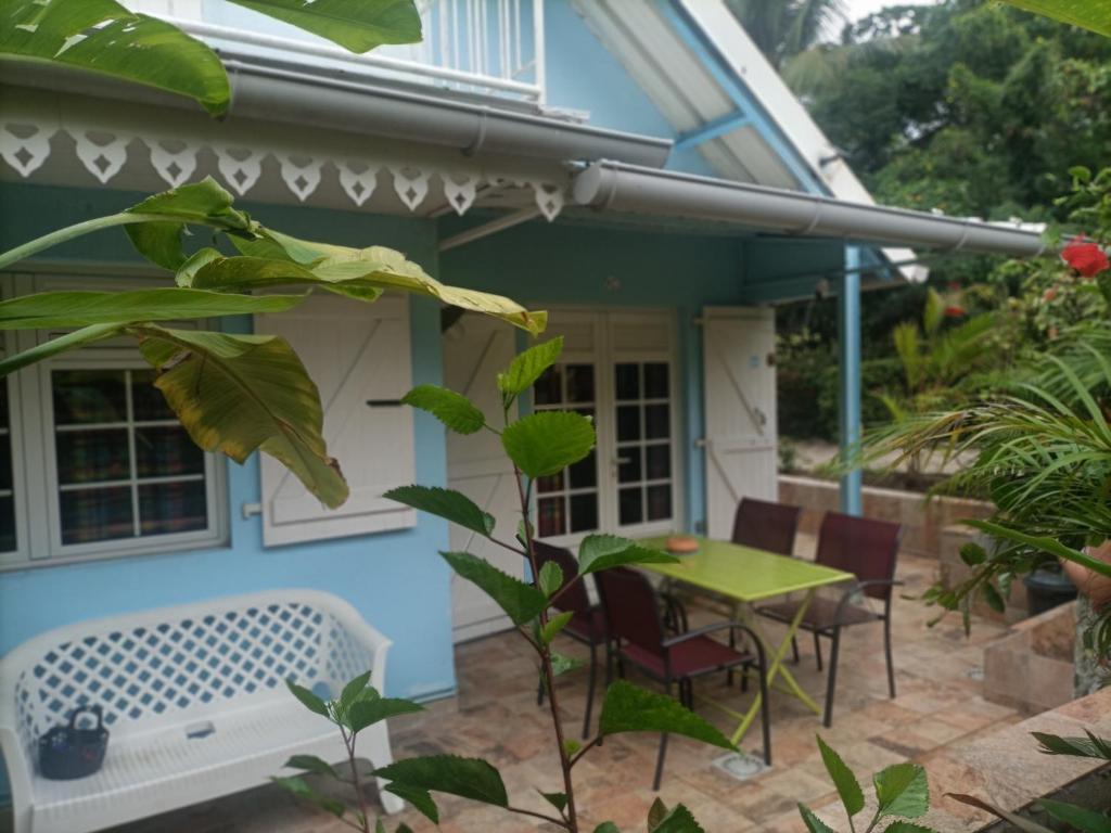 eine Terrasse mit einem Tisch und Stühlen vor einem Haus in der Unterkunft le colibri ble in Sainte-Anne