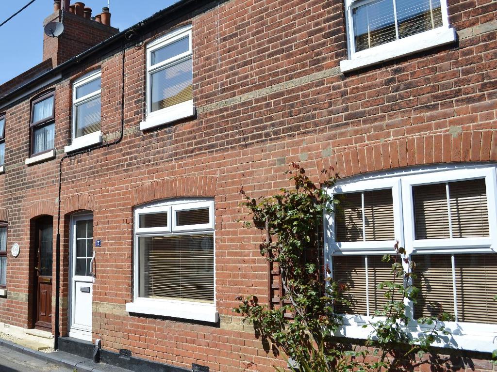 a red brick building with white windows on a street at Beachcomber in Mundesley