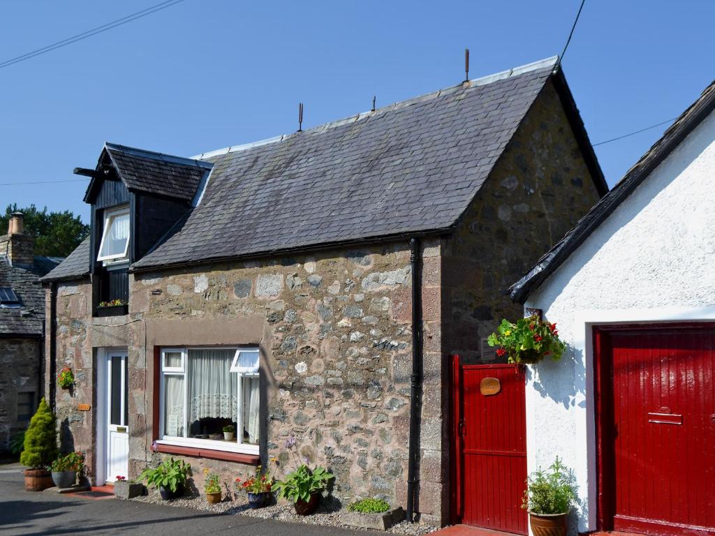 uma antiga casa de pedra com uma porta vermelha em Bakehouse Cottage em Balnald