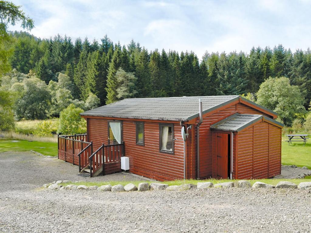 a small wooden cabin with a porch and a deck at Larch Cottage - S4428 in Kirkton of Glenisla