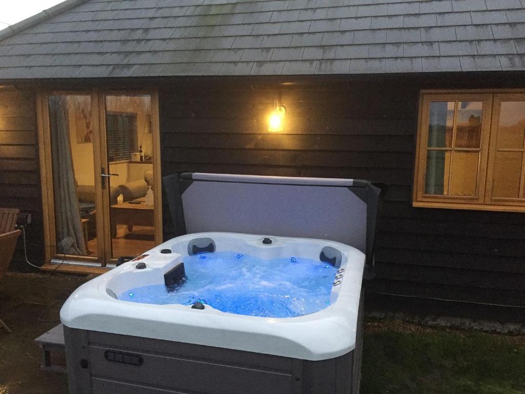 a hot tub sitting outside of a house at Horseshoe Cottage in Alkham