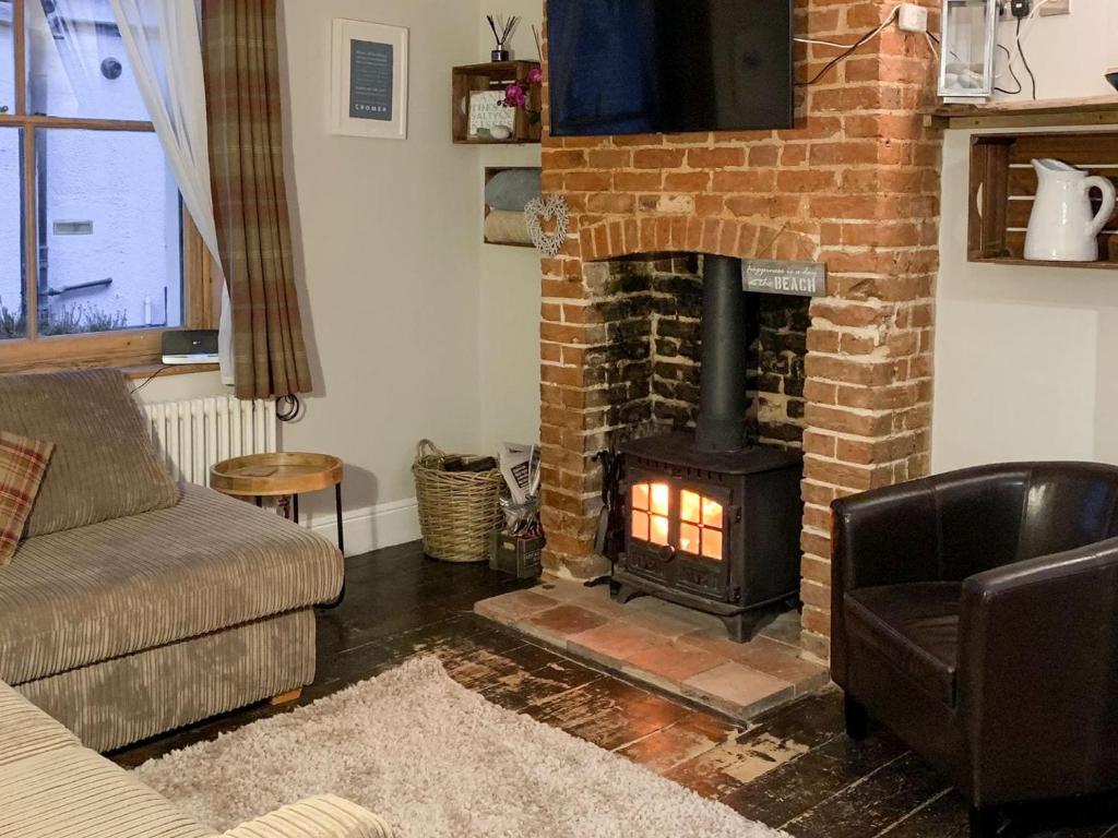 a living room with a brick fireplace and a couch at Melrose Cottage in Cromer