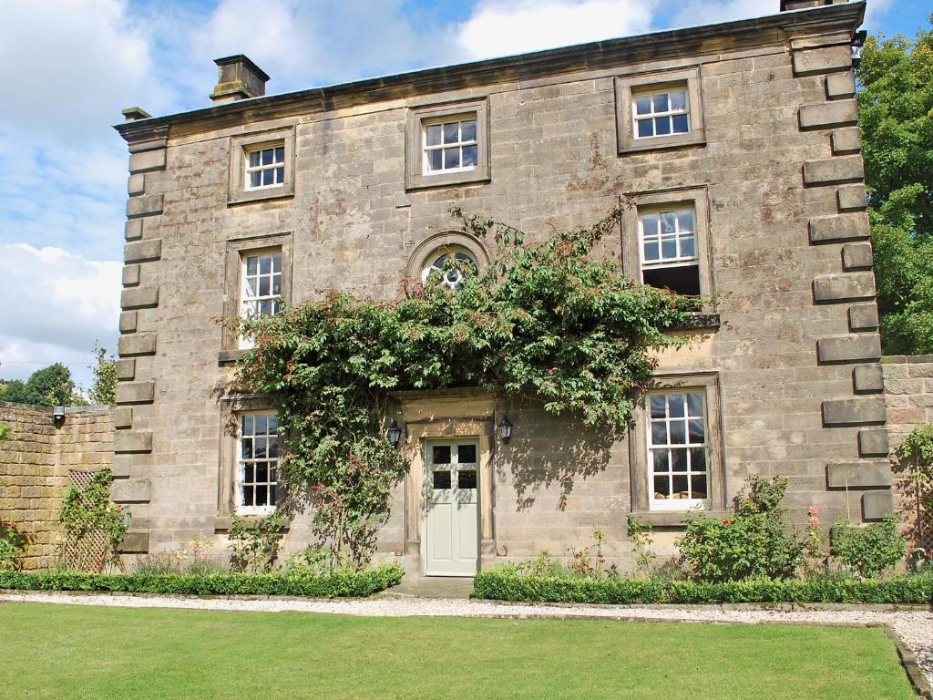 a large stone building with a white door at Bradley Hall in Stanton in Peak