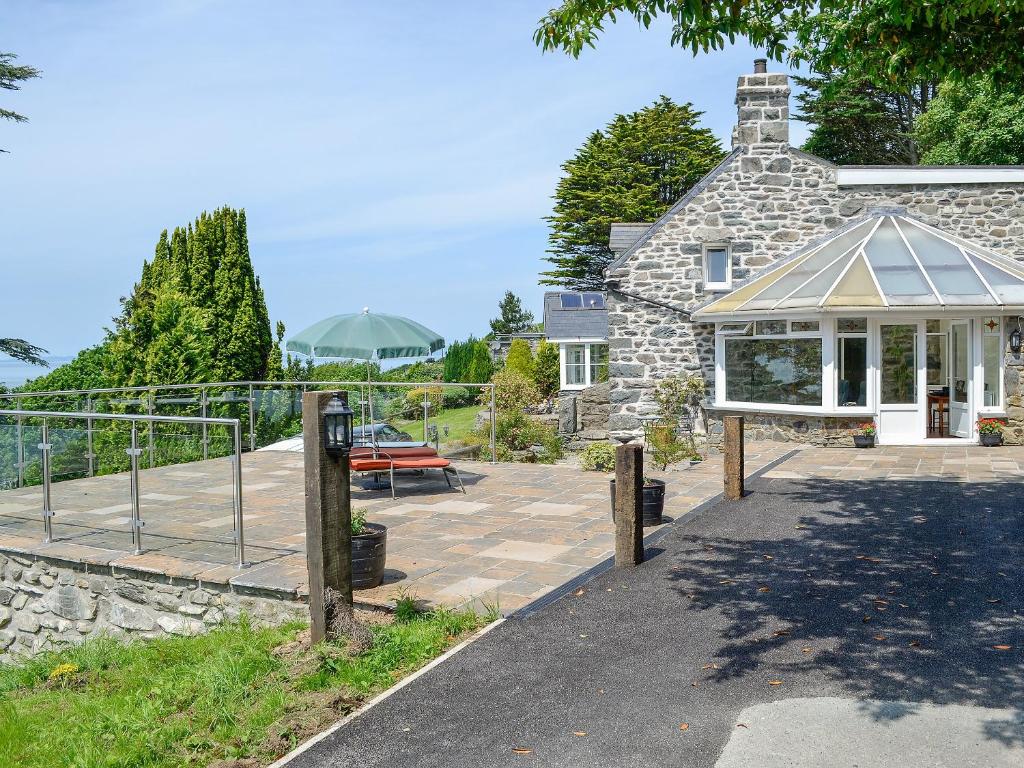 a stone house with a patio and a bench at Cedar Rest in Llanaber