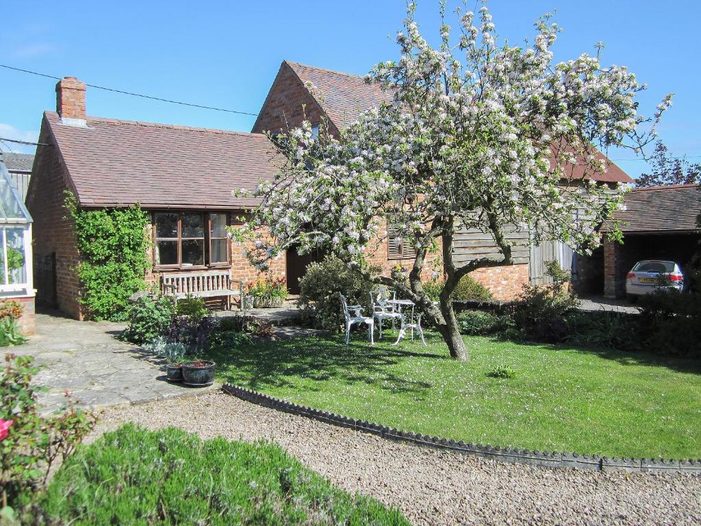 a house with a flowering tree in the yard at Garden Cottage in Hasfield