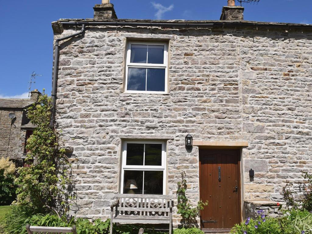 a stone house with a wooden door and a window at Lilac Cottage in Muker