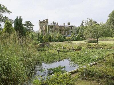 a large building in the middle of a field with a pond at Lochnagar in Largs