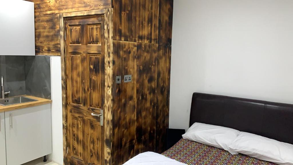 een houten kast naast een bed in een kamer bij Happy house in Birmingham