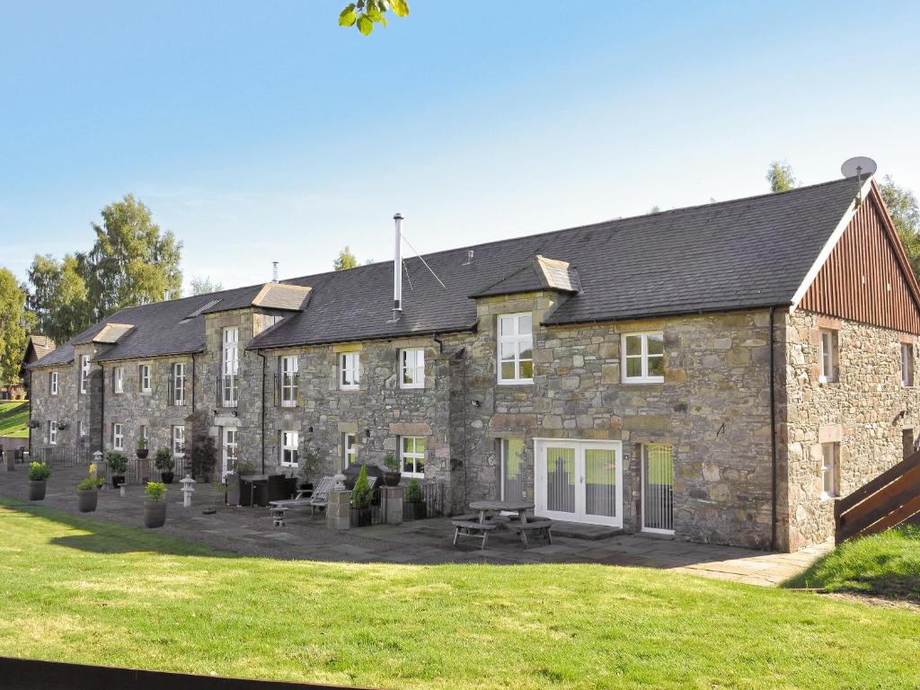 a large stone building with picnic tables in front of it at The Old Granary in Ballindalloch