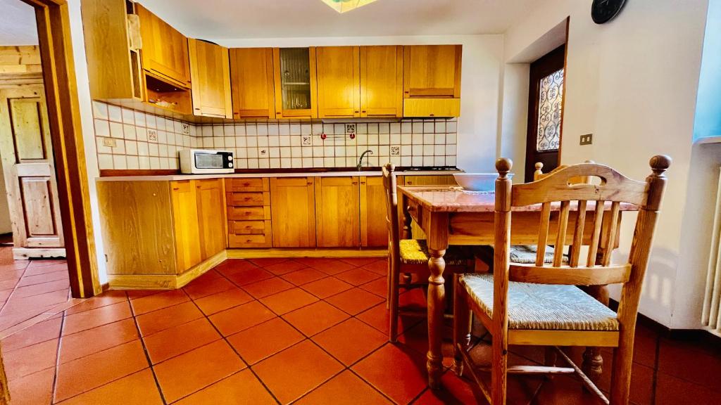 uma cozinha com armários de madeira e uma mesa e cadeiras em PredazzoHouse em Predazzo