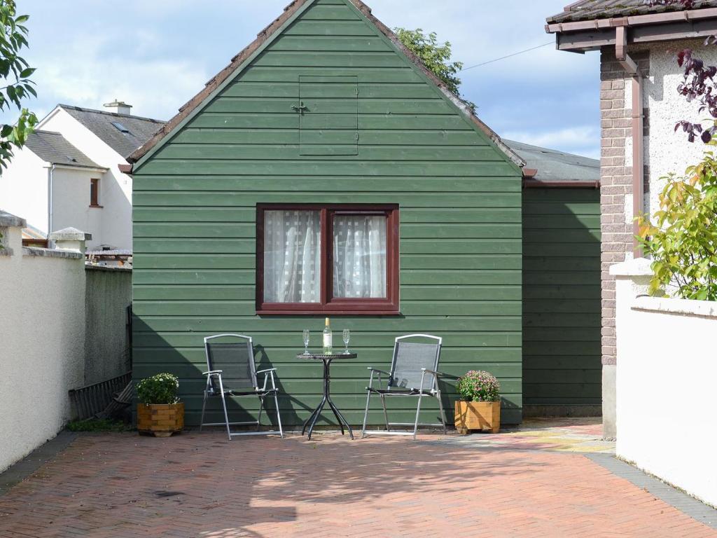 una casa verde con mesa y 2 sillas en Kimberly Cottage, en Alness