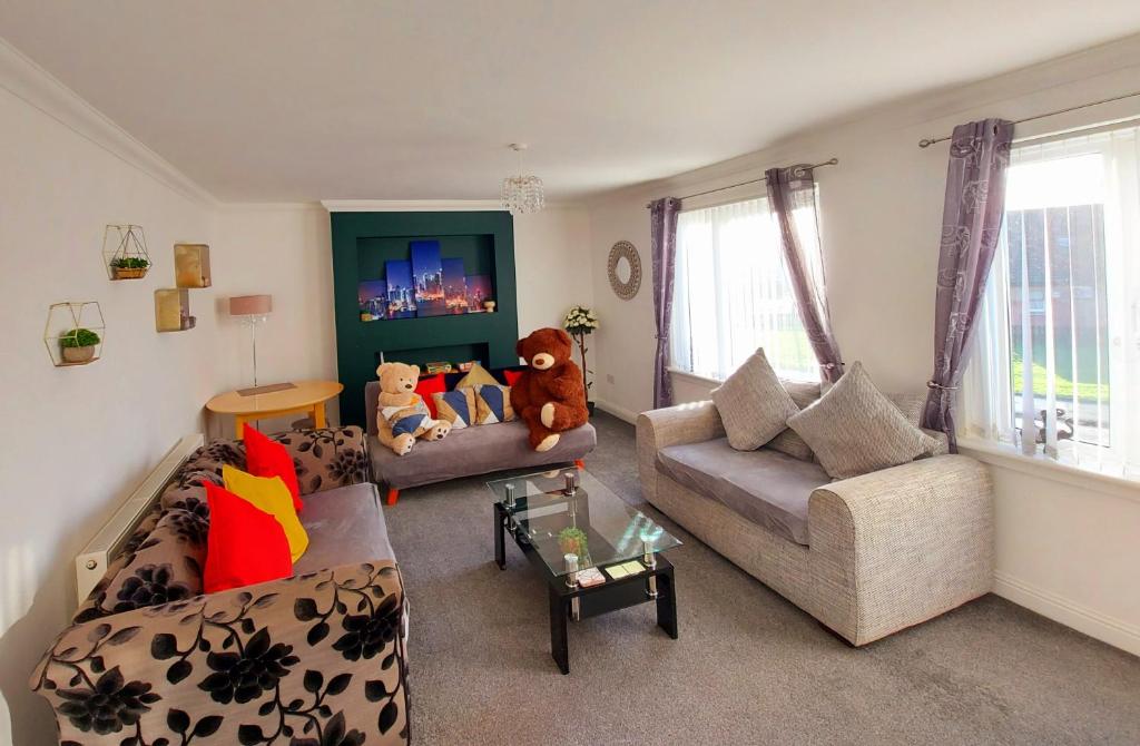 una sala de estar con 2 sofás y un osito de peluche en Teddy Bears' 3-bedroom Maisonette en Saltcoats