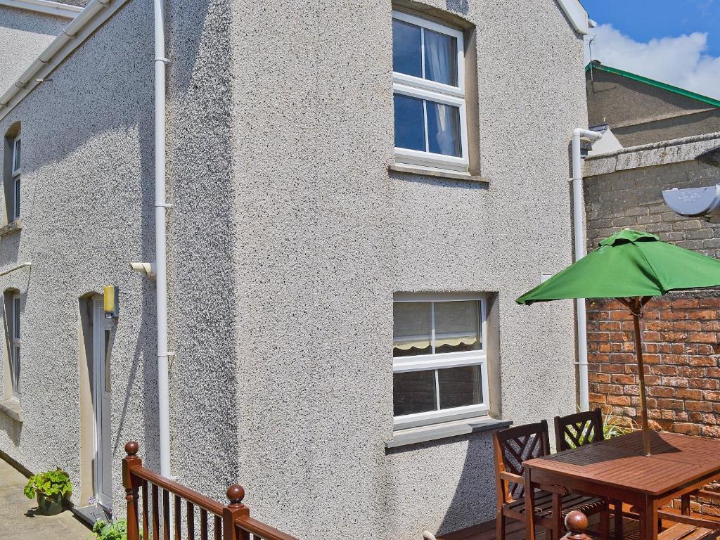 a patio with a table and a green umbrella at Elens Place in Tywyn