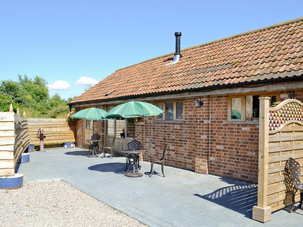 a brick building with a patio with tables and umbrellas at The Parlour in Arlingham
