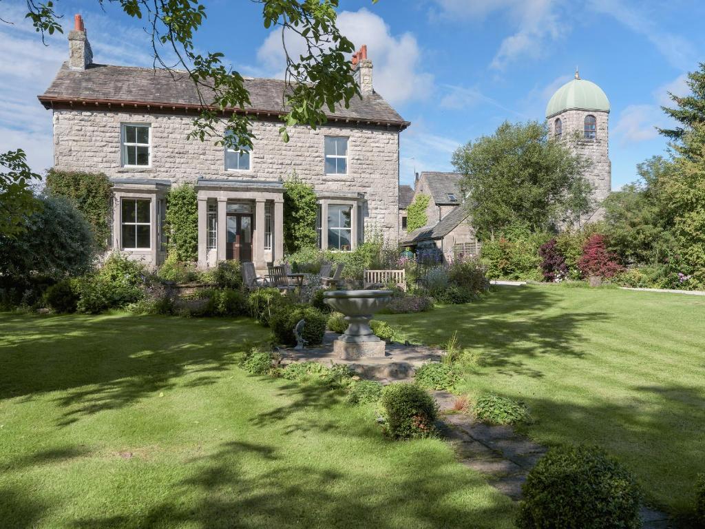 an old stone house with a fountain in the yard at Hazel Grove House in Beetham