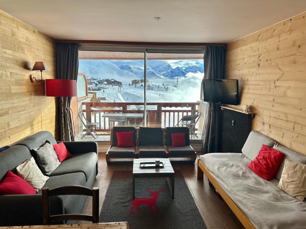 een woonkamer met banken en uitzicht op een berg bij Appartement plein sud, au pied des pistes, vue imprenable in Huez