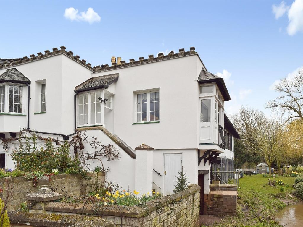 a white house with a stone wall at Riverside in Alcester