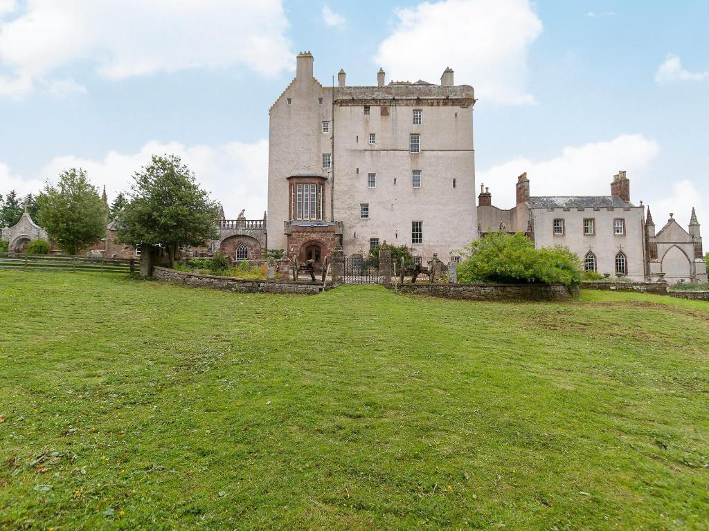 a castle on a hill with a grass field at Symbister Suite in Turriff